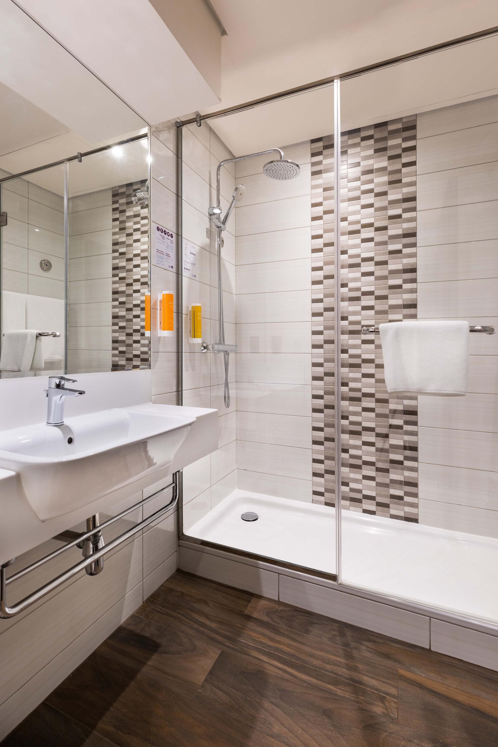 Modern hotel bathroom with glass shower and shower controls