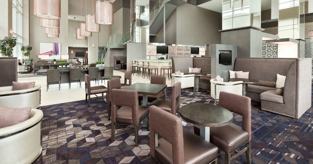 Embassy Suites Charlotte Uptown hotel lobby with modern lounge seating, dining tables, and tall ceilings
