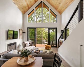 Scandinavian-inspired 1BR cabin with floor-to-ceiling windows and a skylit king bed. Enjoy a stone fire pit, private deck, and peaceful forest views. Perfect for romantic spring escapes and quiet mountain stays. - Young Harris - Living room
